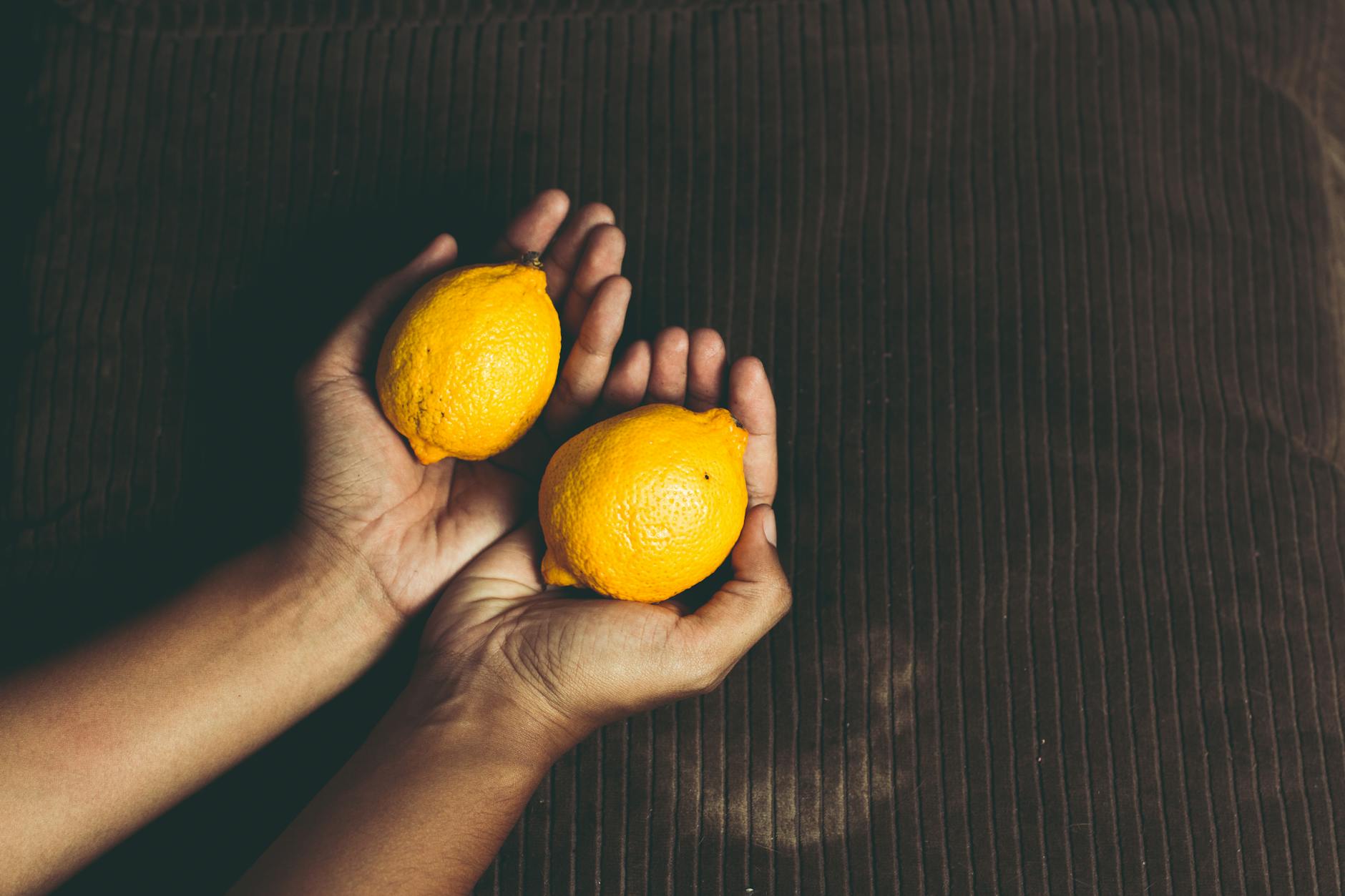 Hand hält einen orangefarbenen Vibrator vor minimalistischem lila Hintergrund