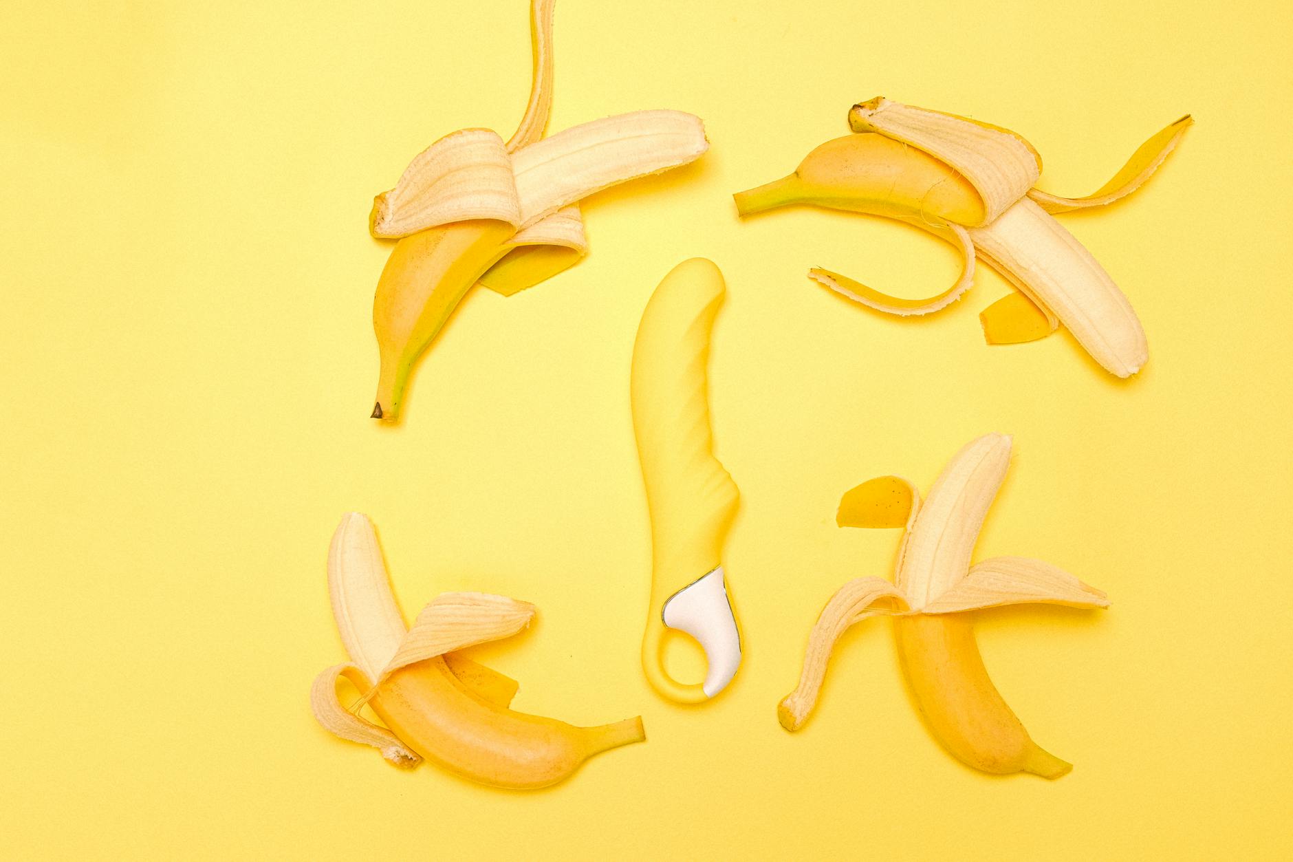 Gelber Lemon Vibrator auf gelbem Hintergrund, umgeben von frischen Zitronenscheiben
