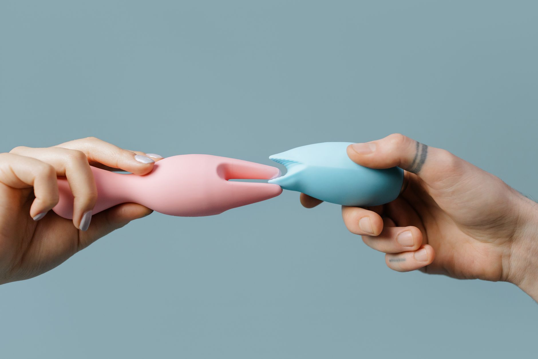 Hand mit weißen Nägeln hält eine Zitrone vor einem weichen rosa Hintergrund