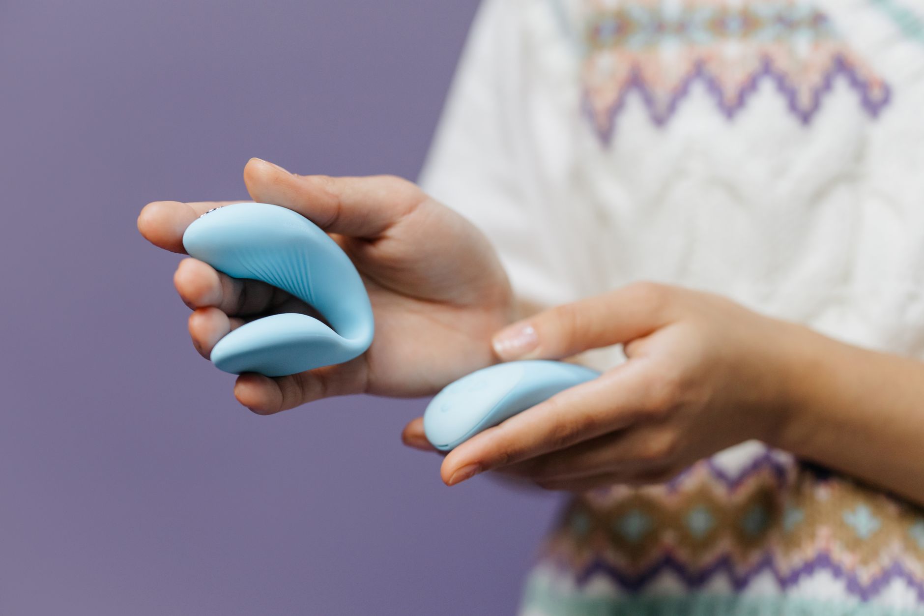 Nahaufnahme von Händen, die einen eleganten Lemon Vibrator in sanftem blauem Licht halten