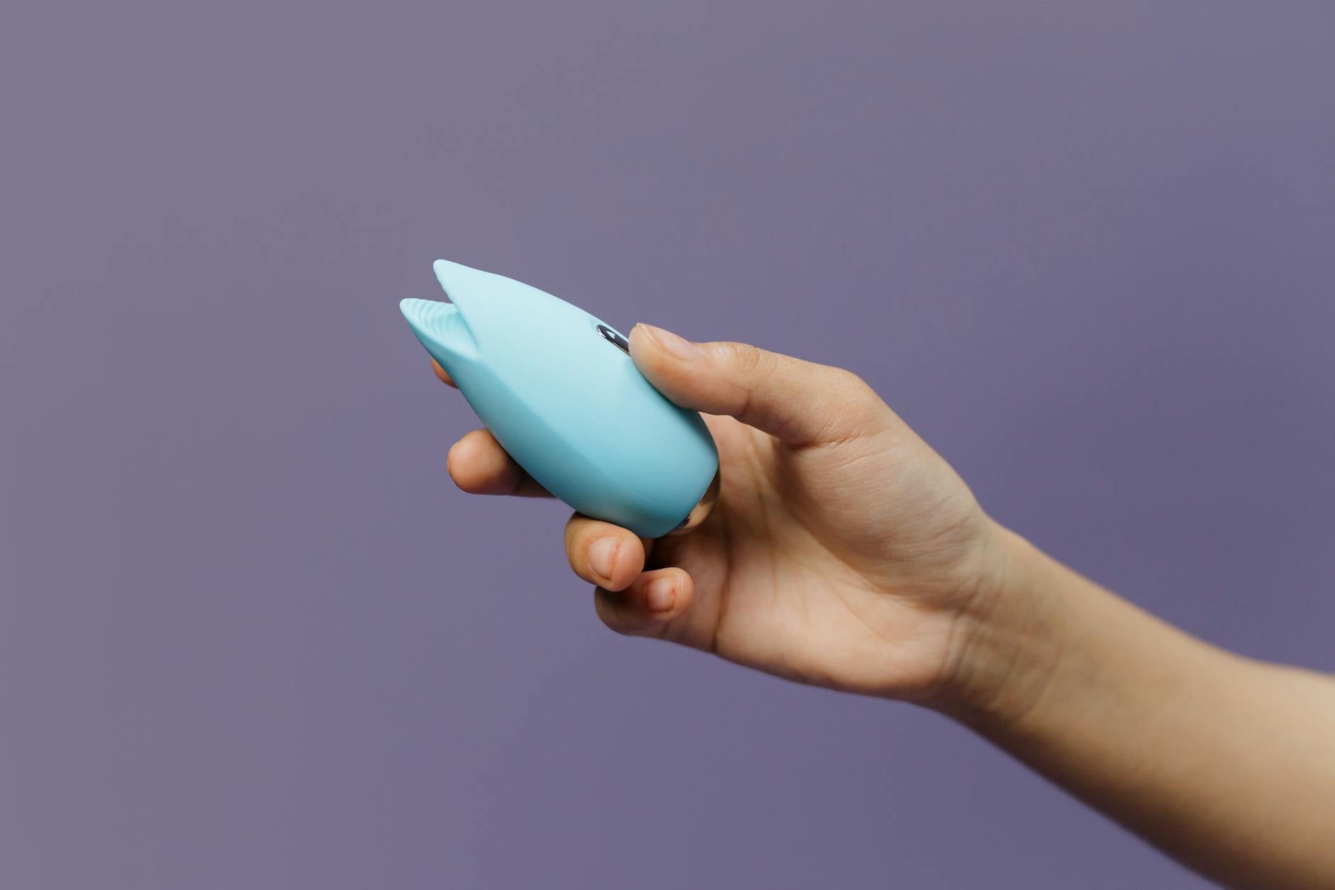 Frau hält blaue Silikonvibrator gegen farbigen Hintergrund